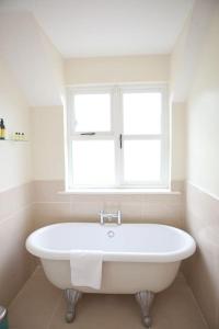 baño con bañera blanca y ventana en The River House en Slane