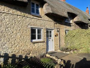 an old stone house with a thatched roof at Blackbird Cottage in Kettering