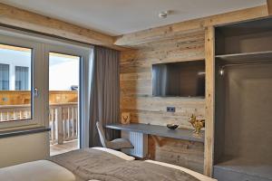 um quarto com uma cama, uma secretária e uma televisão em Sieglhub Chalets - Appartements - Hotel em Flachau