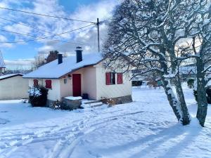 una casa blanca con puertas rojas en la nieve en Petit chalet de montagne avec espace extérieur, en Labaroche