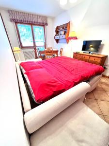 1 cama grande de color rojo en una habitación con escritorio en Stella Alpina, en Tarvisio