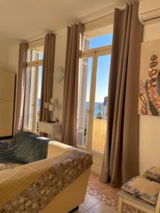 a bedroom with a bed and a large window at Menton centre Vue imprenable sur mer et jardin Biovès in Menton