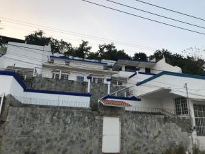 una casa bianca con finiture blu e un muro di pietra di Hotel Sociedad y Maristas a Tecolutla