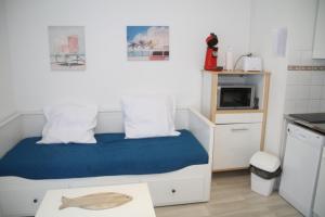 a small bedroom with a bed with a blue blanket at APPARTEMENT LE DAUPHIN in Cap d'Agde