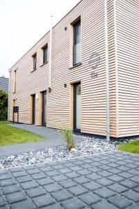 a large wooden building with a sidewalk in front of it at Ferienhaus "Q" - Wohnung 3 in Zingst