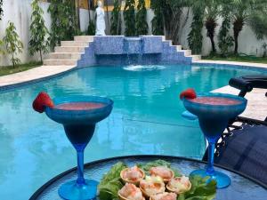 a table with two martini glasses next to a swimming pool at Casa Duplex Privada con Piscina with Ride from Airport in Panama City