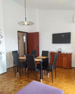 a dining room with a table and chairs and a flat screen tv at Apartments Kočović in Peroj