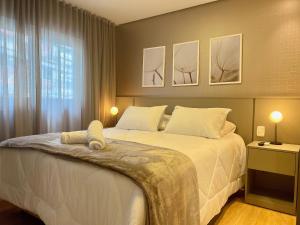 ein Schlafzimmer mit einem großen weißen Bett mit drei Bildern an der Wand in der Unterkunft Apartamentos Solar da Garibaldi CENTRO by Achei Gramado in Gramado + 98 Fotos