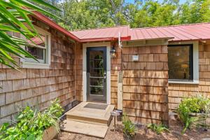 une petite maison avec un toit rouge et une terrasse couverte dans l'établissement Gull Guest Cottage - 757 Ocean Blvd, à Saint Simons