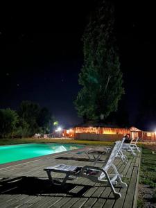 two chairs sitting on a deck near a swimming pool at night at Parcela de agrado orilla de lago in El Estero