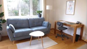 ein Wohnzimmer mit einem Sofa, einem Tisch und einem Schreibtisch in der Unterkunft Wohnen im schönsten Viertel Wiens in Wien