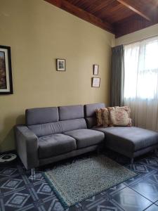 a living room with a couch and a window at The Cozy Cactus House Cartago Centro English Spoke in Cartago