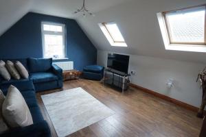 a living room with a blue couch and two windows at Belfast Loft in Belfast