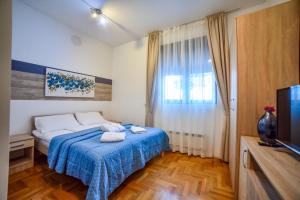 una camera da letto con un letto con una coperta blu e una TV di Ambasador Zlatibor a Zlatibor