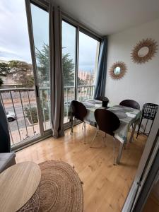 - une salle à manger avec une table, des chaises et de grandes fenêtres dans l'établissement Petit T2 proche de la plage, à Sète