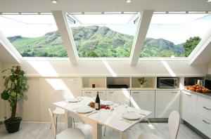 a white kitchen with a table and chairs and windows at Buzzard's Reach formerly Rose Loft Coniston in Coniston