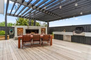 a patio with a table and chairs and a fireplace at Lavish at the Lake in Taupo