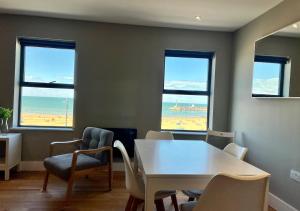 a dining room with a table and chairs and windows at Margate Main Sands Sea views Central Location Sleeps 4 in Kent