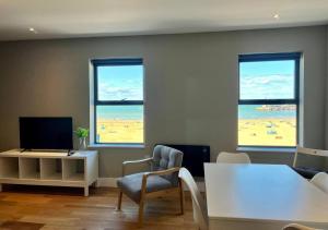 a living room with three windows and a table and chairs at Margate Main Sands Sea views Central Location Sleeps 4 in Kent