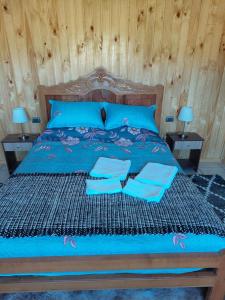 Una cama con sábanas azules y almohadas azules. en Cabaña Loft Curaco de Vélez en Curaco