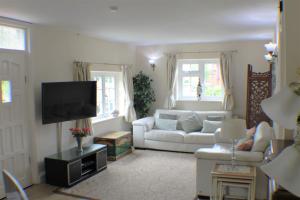 a living room with a white couch and a tv at Moleside Cottage in Marden