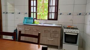 a kitchen with a sink and a stove at Casas Jacatirão in Ubatuba
