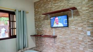 a flat screen tv hanging on a brick wall at Casas Jacatirão in Ubatuba