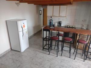 a kitchen with a refrigerator and some bar stools at La Ponderosa in Caleta Olivia