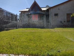 uma casa com uma cerca e um jardim de relva em La Ponderosa em Caleta Olivia
