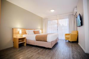 a hotel room with a bed and a chair at Punta Trouville Hotel in Montevideo