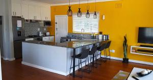 a kitchen with yellow walls and a counter with bar stools at Rose Holiday Home in Durban