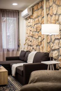 a living room with a couch and a stone wall at Maison d' Alice 1 in Tríkala