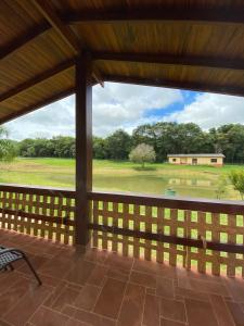 um alpendre com vista para um campo e um edifício em Vale Das Águas Fazenda Resort em Águas de Santa Barbara