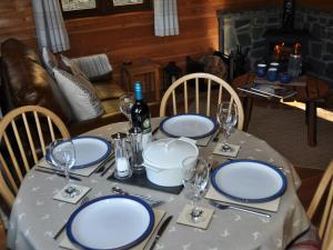 una mesa con platos azules y blancos y copas de vino en Cairnhill Lodge - Award-Winning Luxury Highland Retreat en Blairgowrie