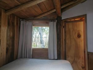 a bedroom with a bed and a window at Cabaña Amor de los Tronquitos, Camino Villarrica in Villarrica