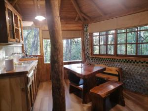 a kitchen with a wooden table and some windows at Cabaña Amor de los Tronquitos, Camino Villarrica in Villarrica