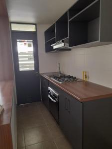 a kitchen with black cabinets and a black door at Departamento Amoblado en Arica in Arica