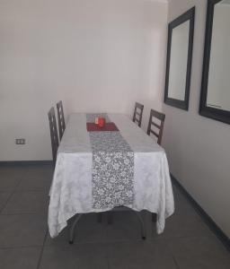 uma mesa de jantar com uma toalha de mesa branca e cadeiras em Departamento Amoblado en Arica em Arica