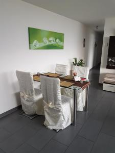 uma sala de jantar com uma mesa e cadeiras brancas em Brissago: 3.5 Zi-Wohnung an extrem ruhiger Lage mit fantastischem Ausblick em Brissago