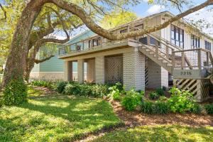 a large house with a tree and a staircase at Three Oaks Beach Cottage - 2215 Bruce Drive in Saint Simons Island