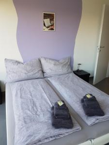 Una cama blanca con dos toallas. en Brissago: 3.5 Zi-Wohnung an extrem ruhiger Lage mit fantastischem Ausblick, en Brissago