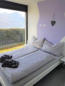 1 dormitorio con 1 cama y ventana grande en Brissago: 3.5 Zi-Wohnung an extrem ruhiger Lage mit fantastischem Ausblick, en Brissago