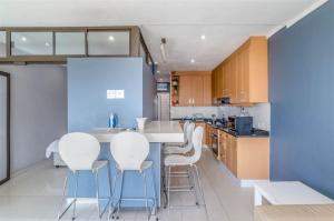 a kitchen with a table and white chairs in it at Cabanas Del Mar 32 in Kingsburgh