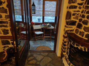 a room with a stone fireplace and a table with a chair at Μaisonette Mary in Palaios Agios Athanasios