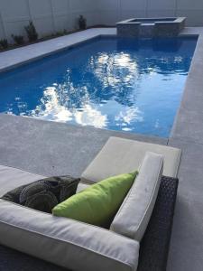 - un canapé avec un oreiller à côté de la piscine dans l'établissement 605 Bartow Guest House, à Kings Terrace