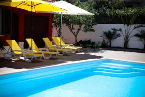 a swimming pool with yellow chairs and umbrellas next to a pool at Sunshine Villa with Heated Pool in Faro