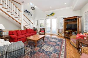 a living room with a red couch and a tv at Satilla Cottage - 15 Coast Cottage Ln in East End