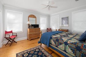a bedroom with a bed and a chair and windows at Satilla Cottage - 15 Coast Cottage Ln in East End