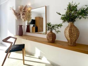 a mirror on a shelf with two vases and a chair at Calistus Mykonos in Mikonos