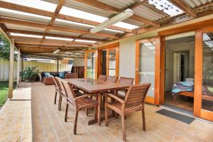 a wooden table and chairs on a patio at Sunbaker Pet Friendly Awards Finalist 4 Mins Walk to Culburra Beach in Culburra Beach